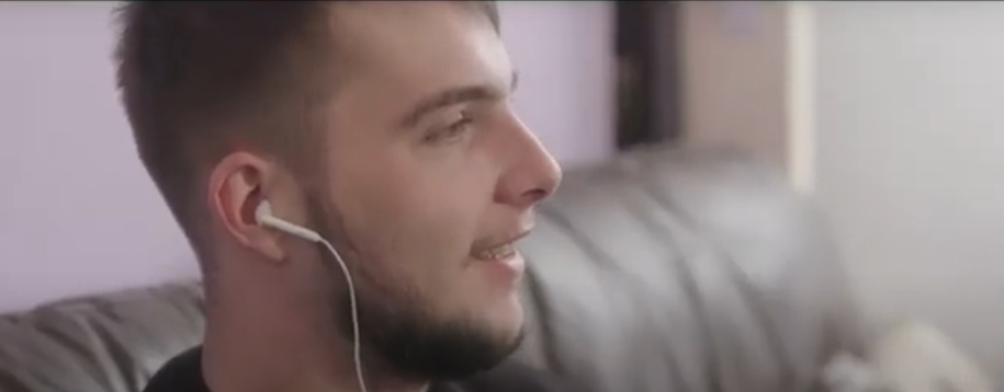 previously homeless tenant Oli, smiling whilst listening to music 