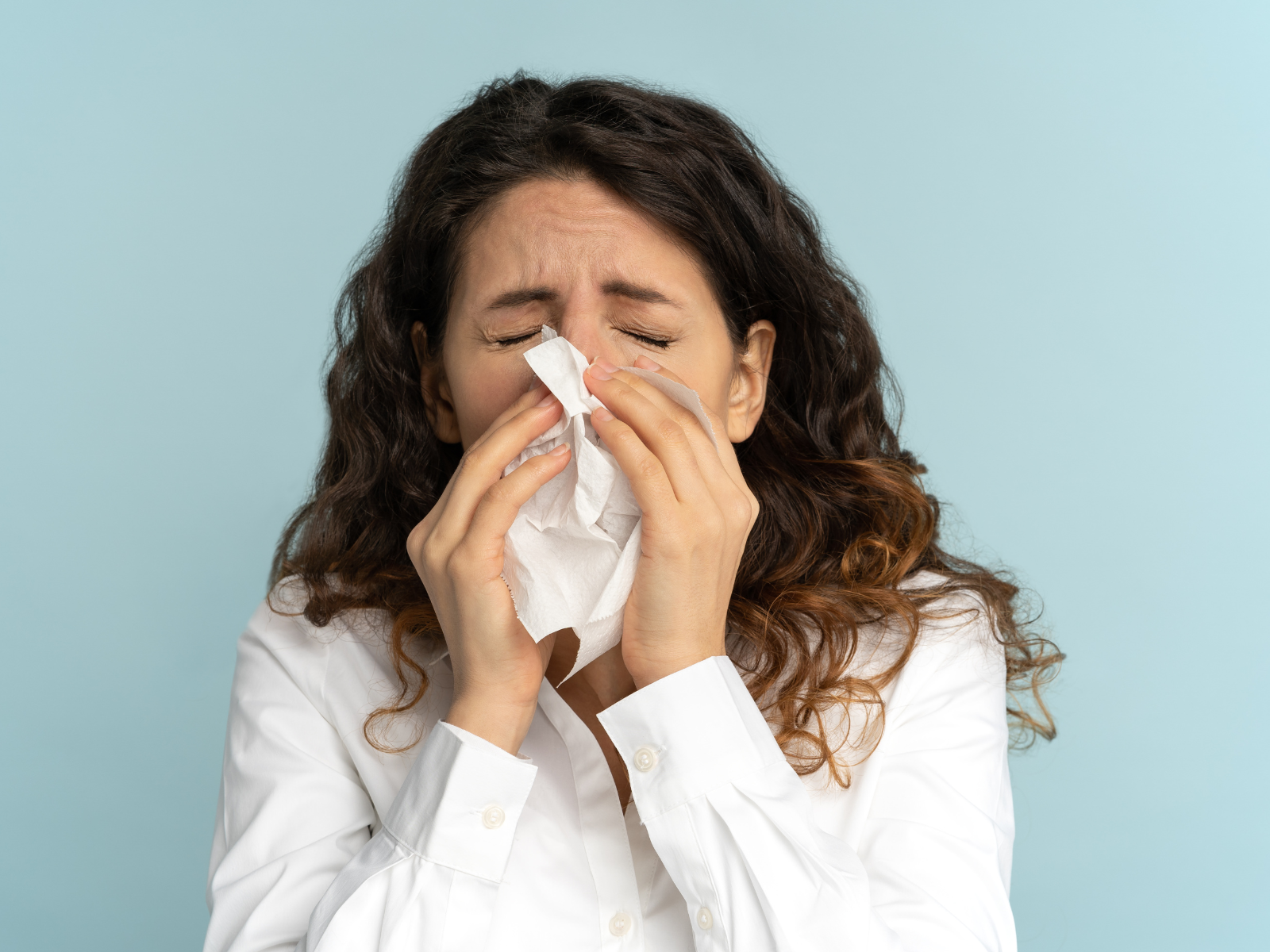 Lady sneezing into a tissue