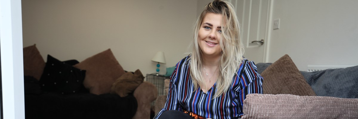 Georgia sitting on her sofa smiling for the photo