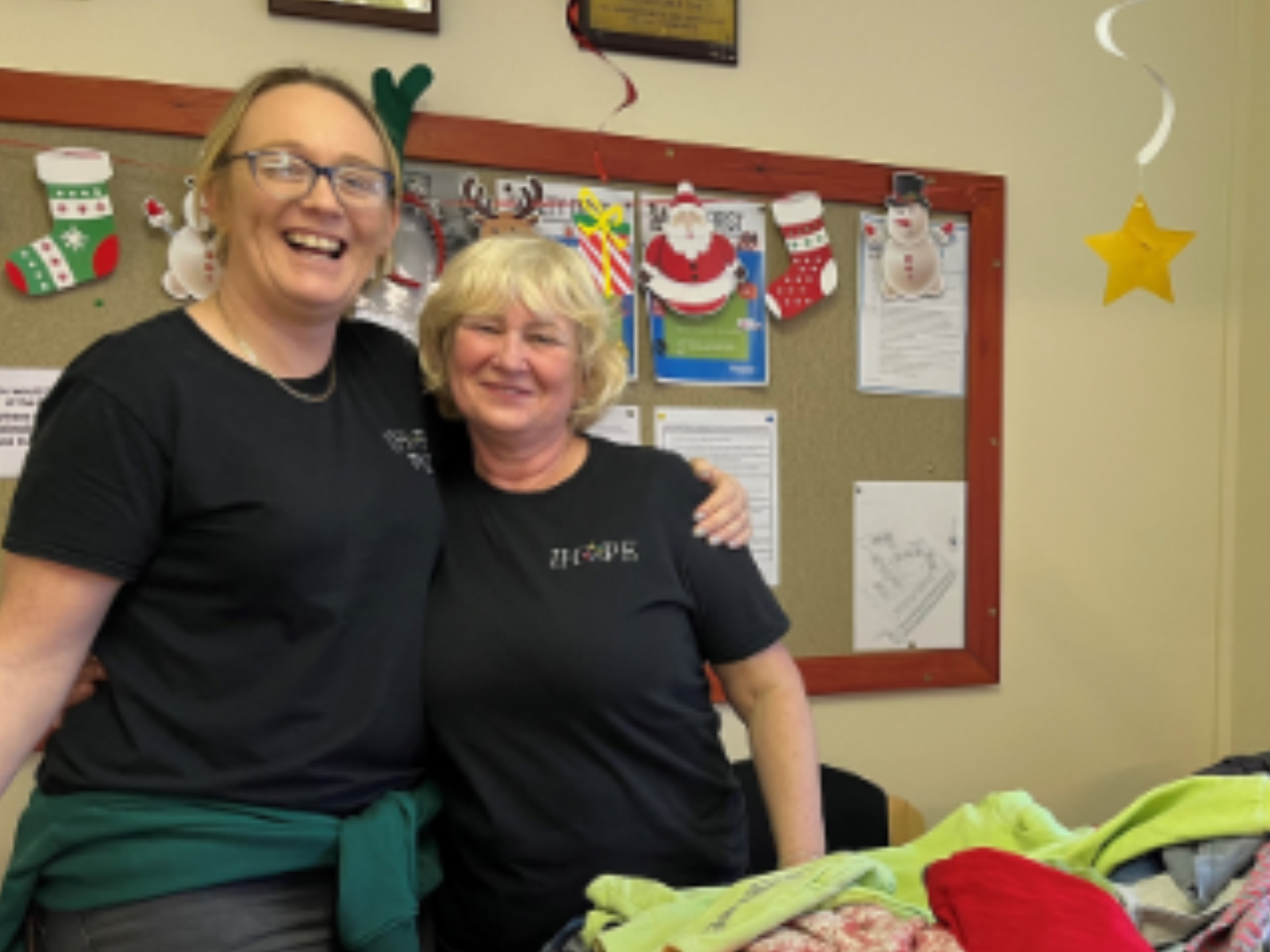 2 ladies smiling with their arms around each other 