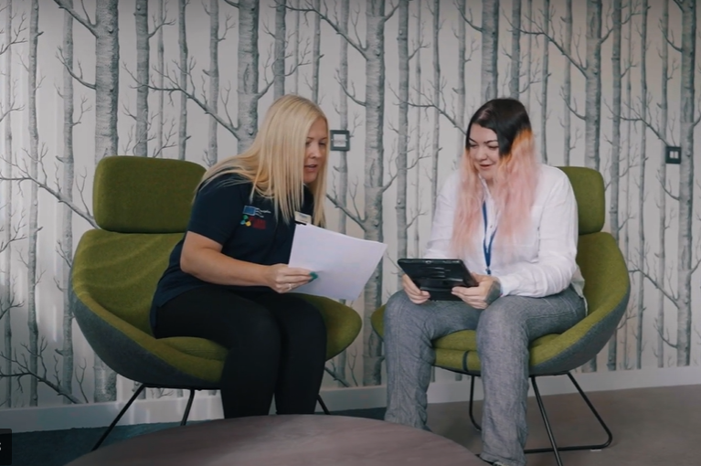 "shows 2 employees Sian, and Cathy, having a discussion"