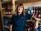 employee smiling in front of stocked shelves at the Fylde community hub
